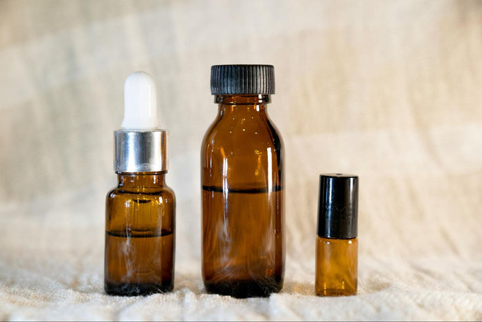 Three amber bottles of different sizes sit in a row with various amounts of serum inside.